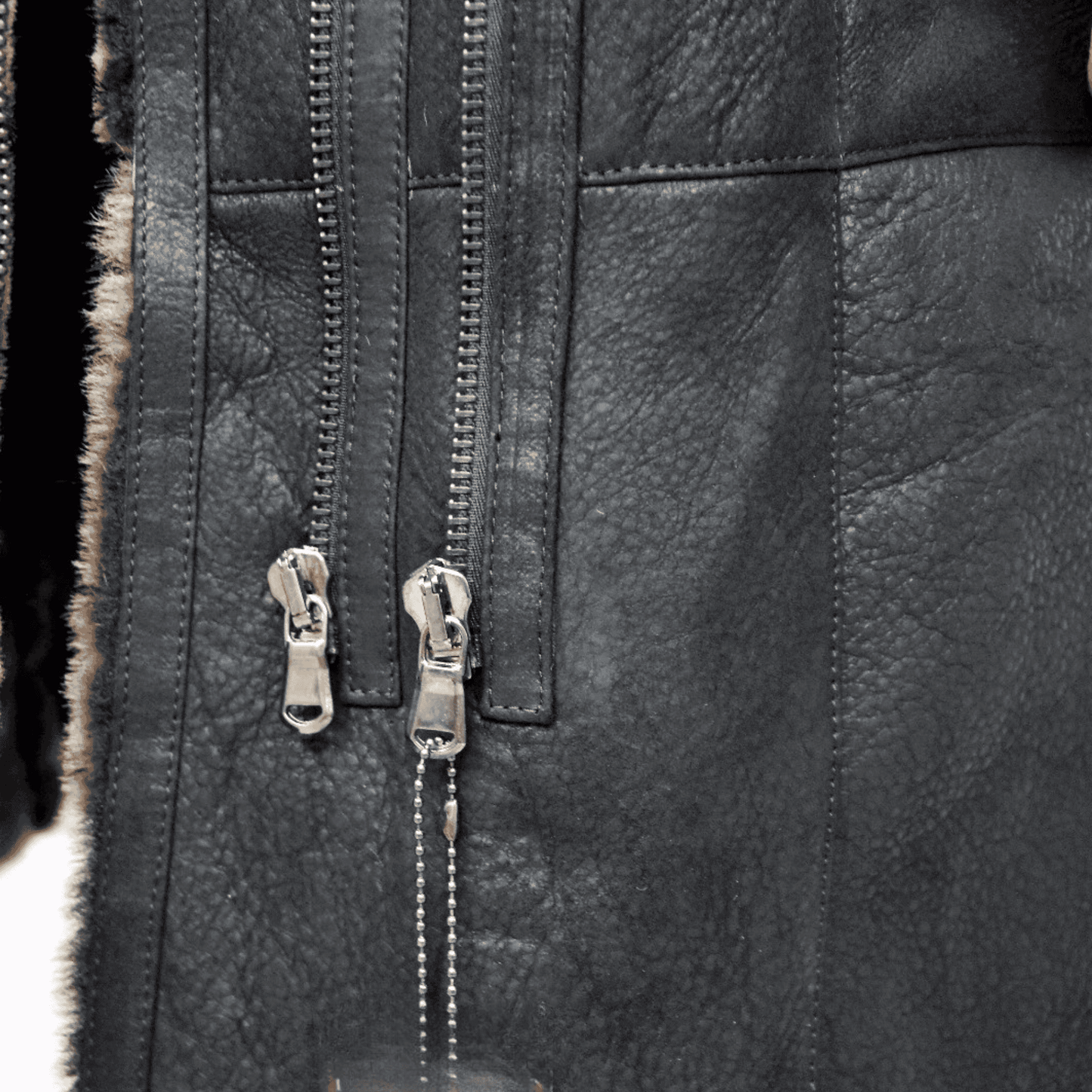Black Sheepskin Shearling Coat close up showing textured leather exterior dual metal zippers and fur trim